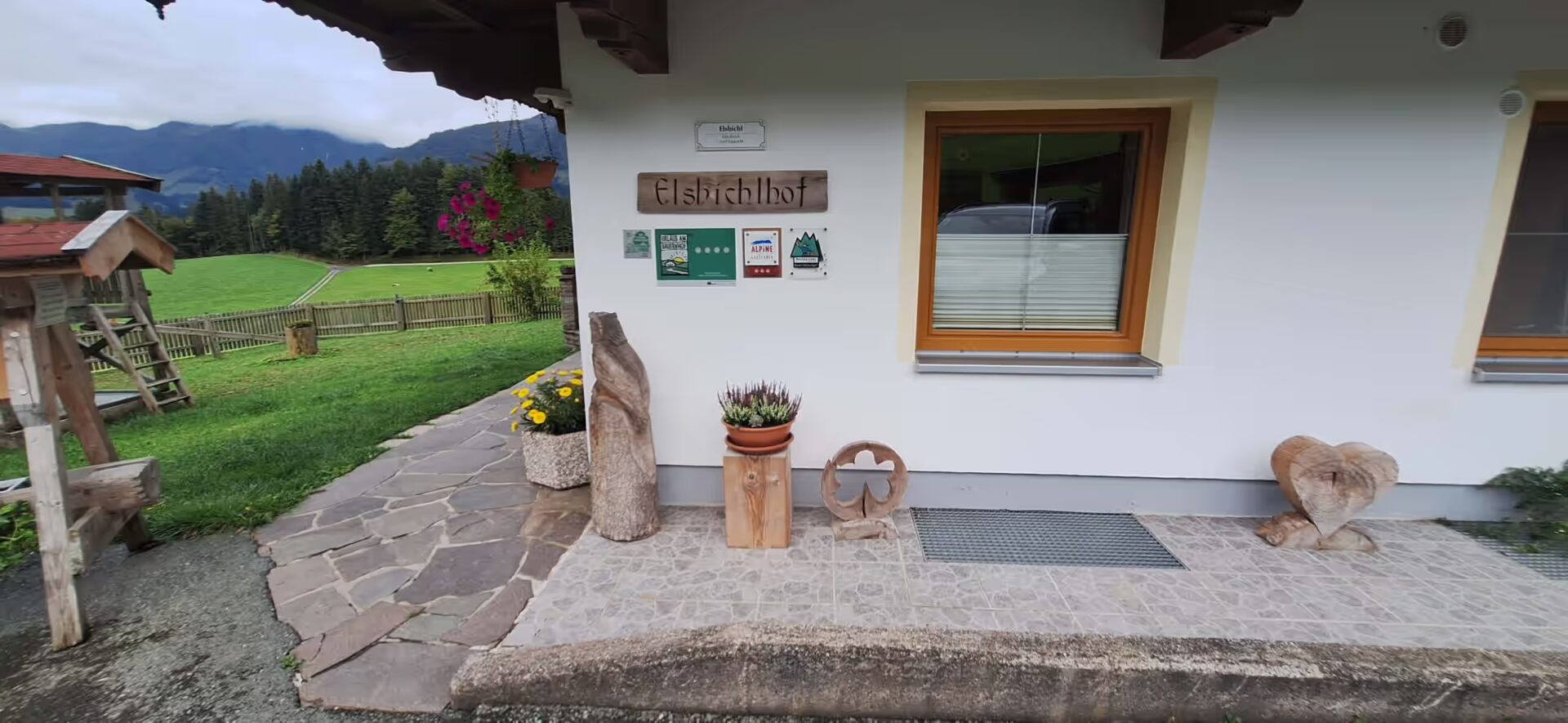 Holzeule, Blume im Topf, Herz aus Holz, Garten im Hintergrund