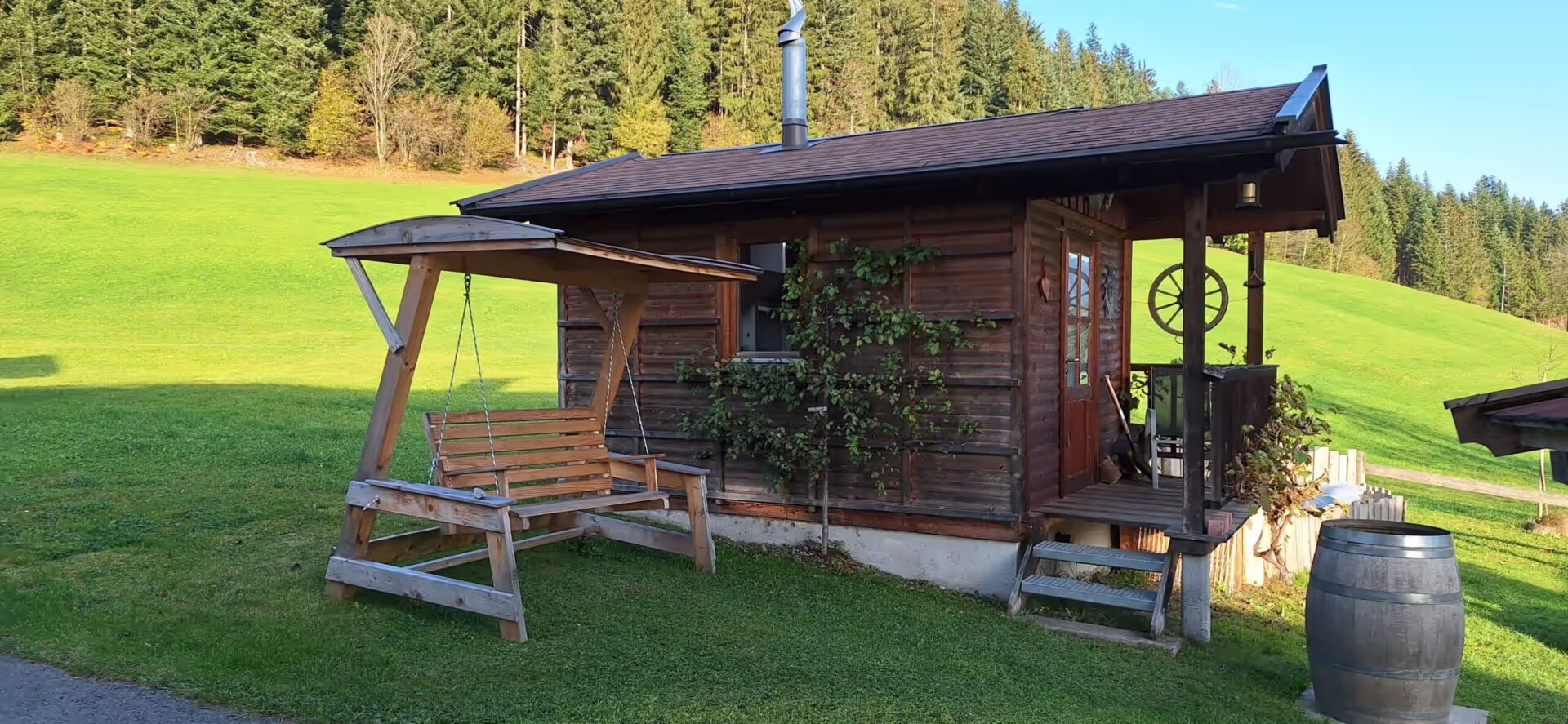 Westernschaukel und nebenbei die Grillhuette mit einem Baum an der Seite