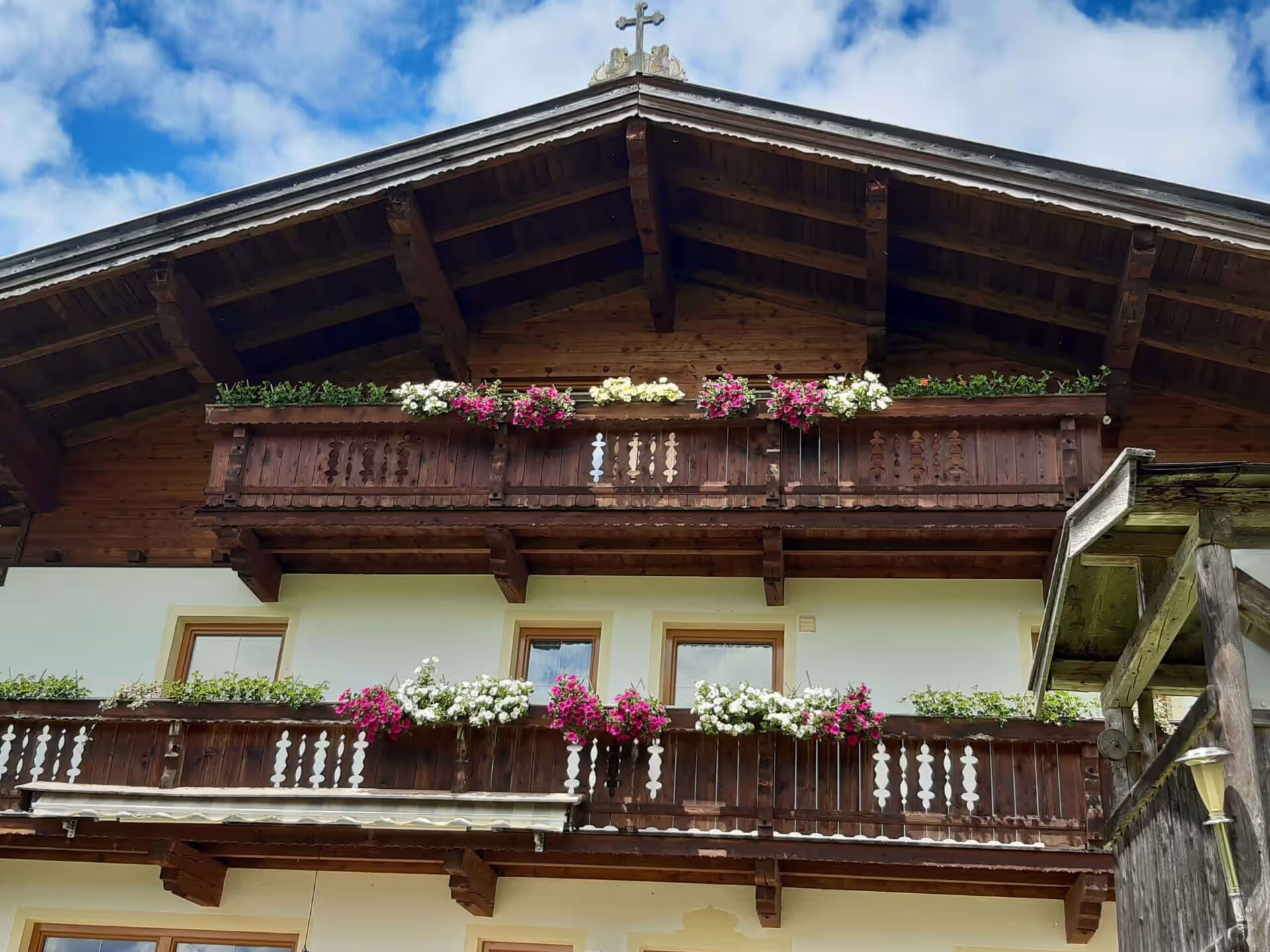 Frontansicht des Hauses, mit weissen und pinken Blumen auf dem Balkon