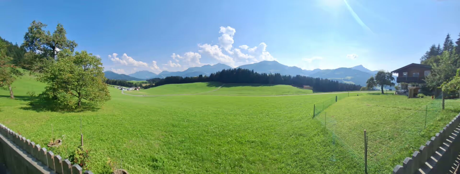 Panoramaaufnahme mit Bergen, Wälder und Wiesen, auch die Nachbarn sieht man