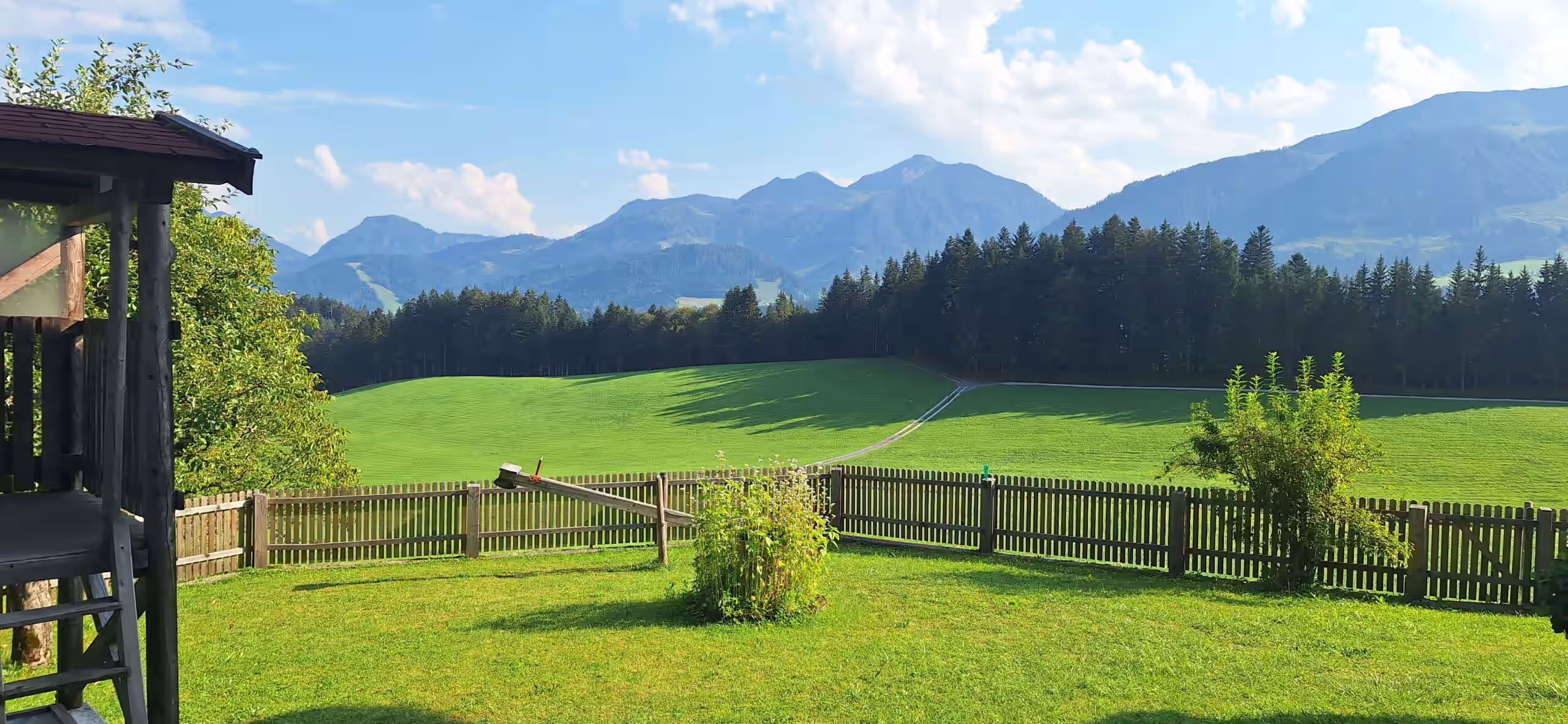 Wippe und Garten im Vordergrund, Hintergrund: verschiedenste Berge