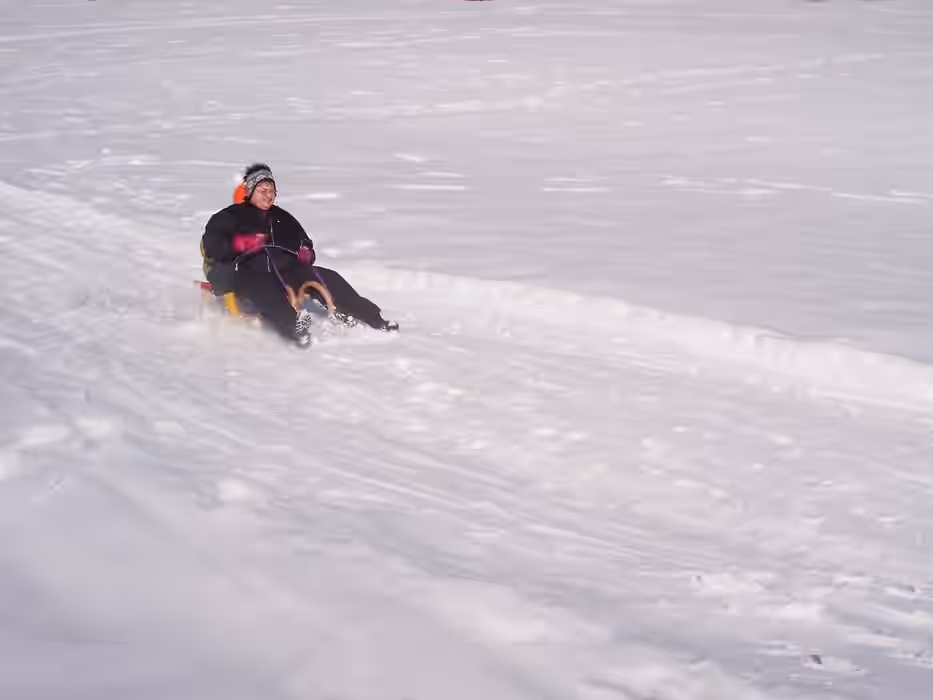 Mutter faehrt mit Kind auf Schlitten und bremst gerade