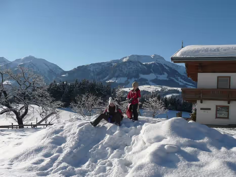 zwei Jungs sind auf dem Schneehuegel und rutschen runter